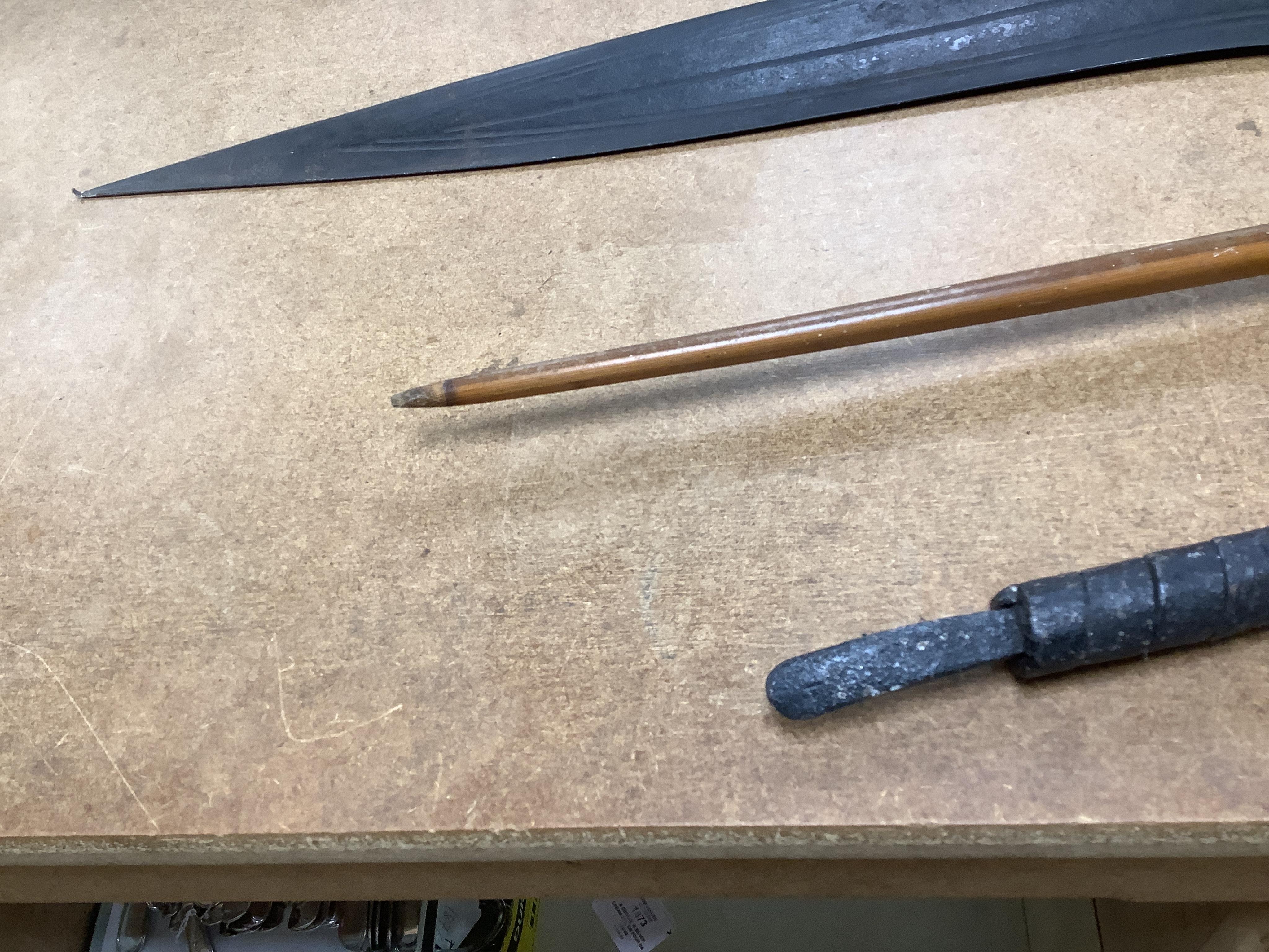 A collection of tribal spears, a fish hook, a cased snooker cue, etc.
